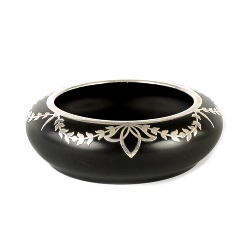 27 - A 1930’S BLACK GLASS AND SILVER INLAID BOWL having swagged leaf work border. (15cm diameter)