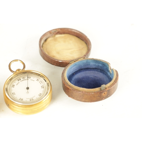 394 - TWO GILT BRASS CASED POCKET BAROMETERS, one in the originally Moroccan leather case, the other signe... 