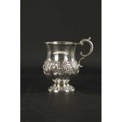 413 - AN IRISH FLORAL EMBOSSED SILVER CHRISTENING MUG, with scroll handle and raised on circular foot. - 1... 