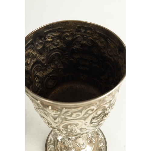 418 - A GEORGE III GIANT-SIZE SILVER GOBLET the body deeply embossed with winged cherub heads, leafing fru... 