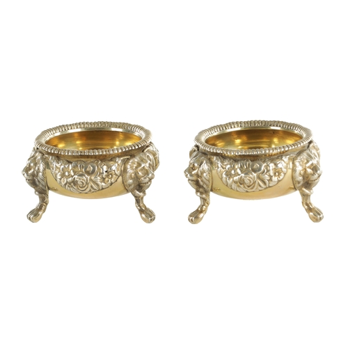 420 - A PAIR OF GEORGIAN SILVER GILT TABLE SALTS with embossed flowerhead design standing on three splayed... 