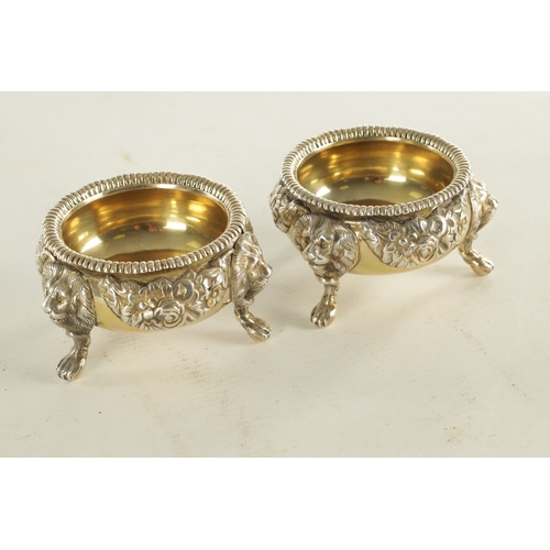 420 - A PAIR OF GEORGIAN SILVER GILT TABLE SALTS with embossed flowerhead design standing on three splayed... 