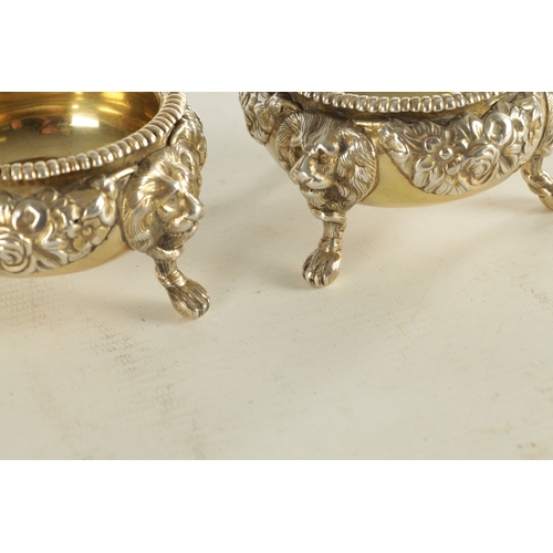 420 - A PAIR OF GEORGIAN SILVER GILT TABLE SALTS with embossed flowerhead design standing on three splayed... 