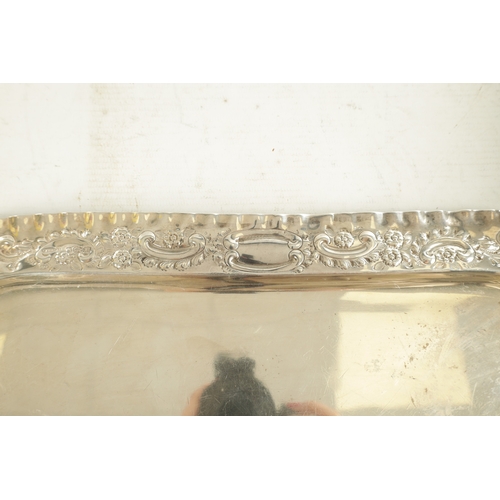 442 - AN EDWARD VII SILVER RECTANGULAR TRAY with florally embossed scroll work crimped border and plain ce... 