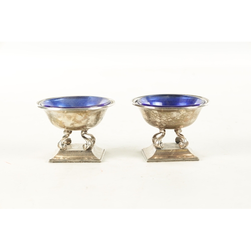 443 - A PAIR OF SILVER SALT CELLARS WITH BLUE GLASS LINERS, raised on scrolled supports and square moulded... 