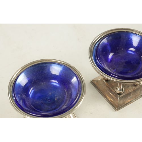 443 - A PAIR OF SILVER SALT CELLARS WITH BLUE GLASS LINERS, raised on scrolled supports and square moulded... 