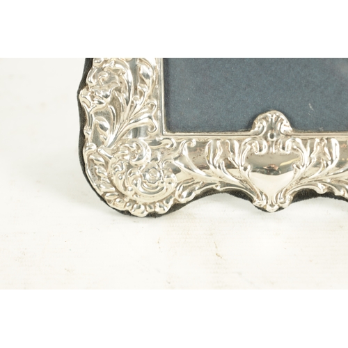 487 - A VICTORIAN STYLE SILVER PHOTOGRAPH FRAME with embossed scrolling leafwork surround and arched top c... 