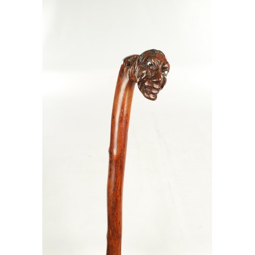 509 - AN EARLY 19TH CENTURY FOLK ART CARVED WALKING STICK the stained branch work shaft with a carved man'... 