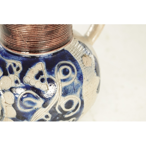 66 - A 19TH CENTURY WESTERWALD GERMAN STONEWARE JUG with blue highlighted incised floral decorations encl... 