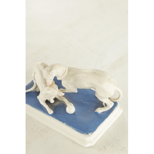 71 - A LATE 19TH CENTURY GERMAN BISQUE PORCELAIN SCULPTURE OF TWO WHIPPETS PLAYING on a blue moulded base... 