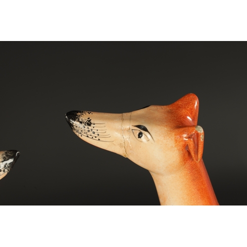 99 - A GOOD PAIR OF 19TH CENTURY STAFFORDSHIRE GREY HOUNDS with hares raised on moulded bases (33cm high)