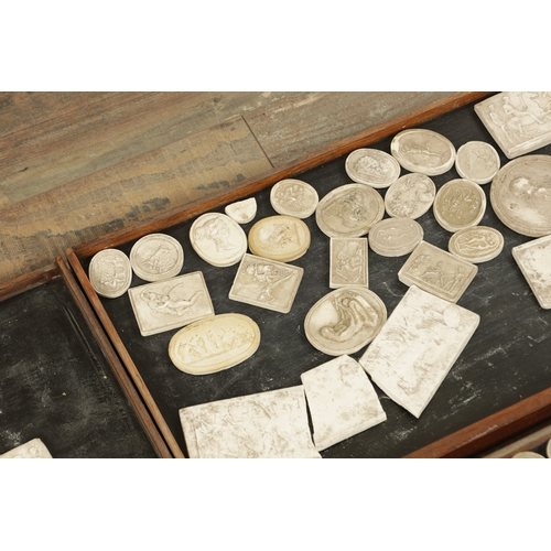 615 - AN EARLY 19TH CENTURY CASED SET OF PLASTER WORK RELIEFS AND BADGES in a mahogany set of drawers of v... 