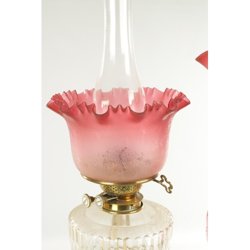 623 - A COLLECTION OF THREE 19TH CENTURY OIL LAMPS, having brass columns on square bases, two with glass c... 