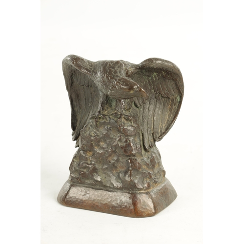 638 - GUSTAV MANZ (1865-1946) A SIGNED BRONZE EAGLE DESK STAND depicted perched on a rocky mound with wing... 