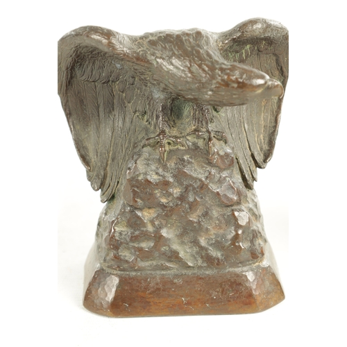 638 - GUSTAV MANZ (1865-1946) A SIGNED BRONZE EAGLE DESK STAND depicted perched on a rocky mound with wing... 