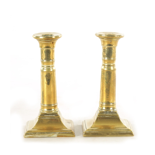 645 - A PAIR OF GEORGE III BRASS CANDLESTICKS with cannon barrel telescopic stems and square bases togethe... 