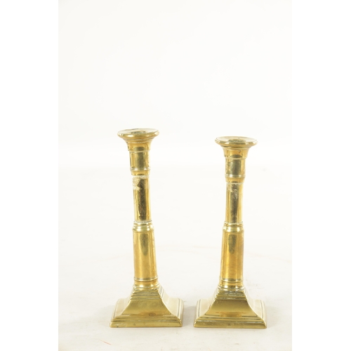 645 - A PAIR OF GEORGE III BRASS CANDLESTICKS with cannon barrel telescopic stems and square bases togethe... 