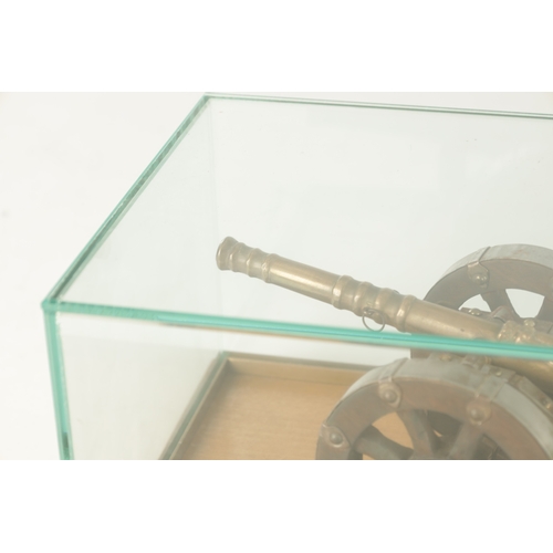 650 - TWO 20TH CENTURY BRONZE MODEL CANNON on wooden carriages - in glass display cabinets (32cm wide )