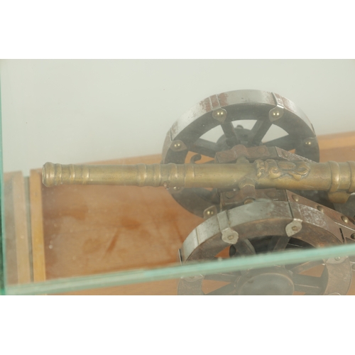 650 - TWO 20TH CENTURY BRONZE MODEL CANNON on wooden carriages - in glass display cabinets (32cm wide )