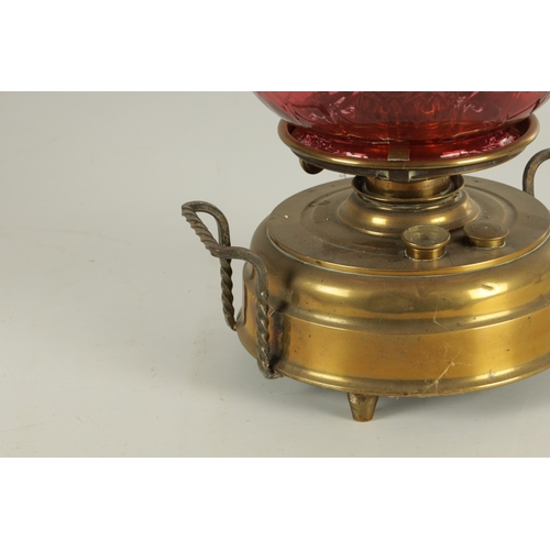 657 - A LATE 19TH CENTURY BRASS HEARTH LAMP the shallow two-handled container base on three small feet sup... 