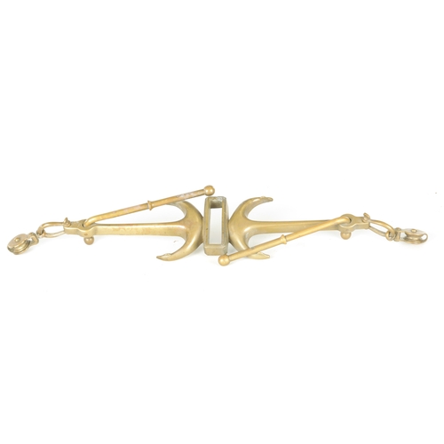 663 - A LATE 19TH CENTURY BRASS HANGING BRACKET with anchors and a pulley to each end. (58cm wide)