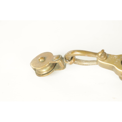 663 - A LATE 19TH CENTURY BRASS HANGING BRACKET with anchors and a pulley to each end. (58cm wide)