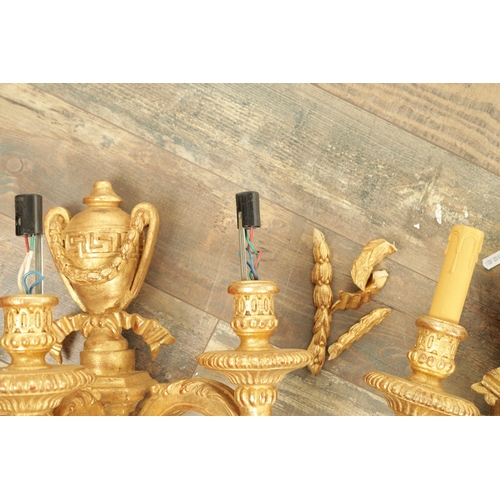 696 - A SET OF FOUR CARVED GILTWOOD ADAM STYLE HANGING WALL LIGHTS with urn-shaped leaf-carved bodies havi... 