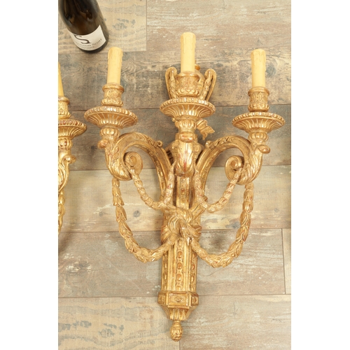 696 - A SET OF FOUR CARVED GILTWOOD ADAM STYLE HANGING WALL LIGHTS with urn-shaped leaf-carved bodies havi... 