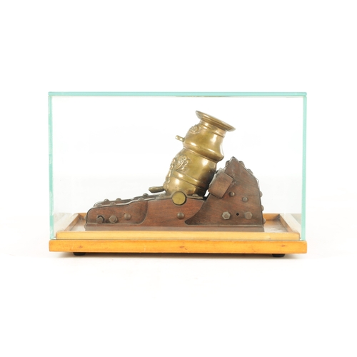 754 - A 20TH CENTURY BRONZE MODEL OF A MORTAR CANNON mounted on a wooden carriage - in a glazed case (21cm... 