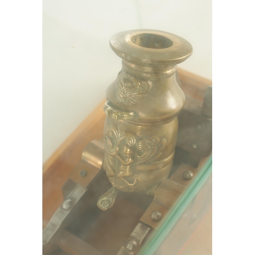 754 - A 20TH CENTURY BRONZE MODEL OF A MORTAR CANNON mounted on a wooden carriage - in a glazed case (21cm... 