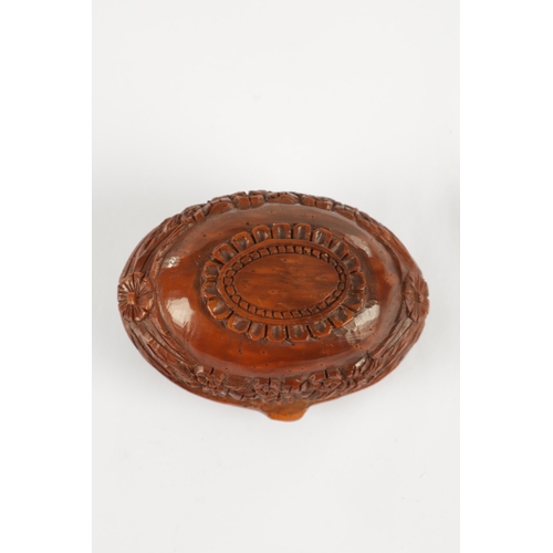 755 - A 19TH CENTURY CARVED COQUILLA NUT SNUFF BOX decorated with a military crest and leaf work border. (... 