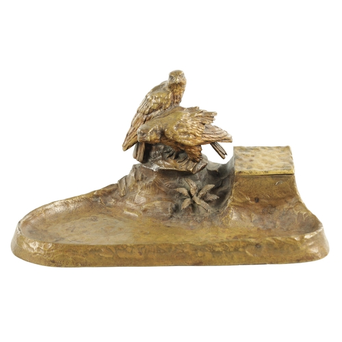 797 - AN EARLY 20TH CENTURY GILT BRONZE PEN AND INK STAND depicting a perched pair of birds of prey on a r... 