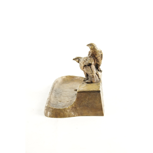 797 - AN EARLY 20TH CENTURY GILT BRONZE PEN AND INK STAND depicting a perched pair of birds of prey on a r... 