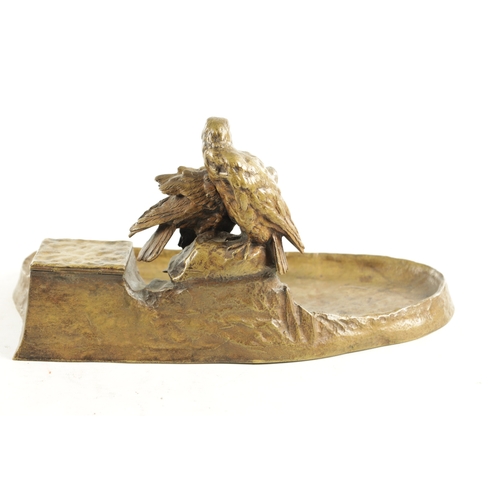 797 - AN EARLY 20TH CENTURY GILT BRONZE PEN AND INK STAND depicting a perched pair of birds of prey on a r... 