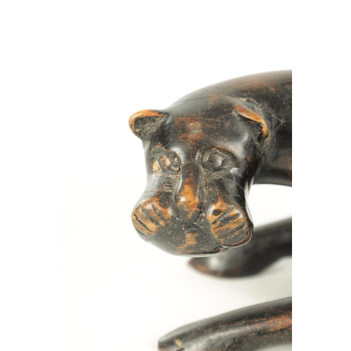 894 - A 19TH/EARLY 20TH CENTURY CARVED STAINED HARDWOOD SCULPTURE OF A RECUMBENT BIG CAT (31cm length)