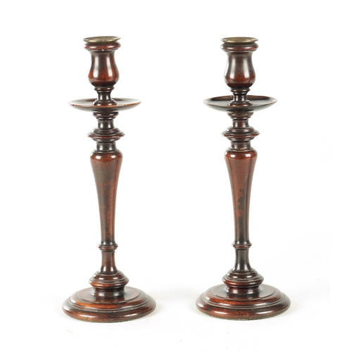 899 - A PAIR OF GEORGE III TURNED MAHOGANY CANDLESTICKS with brass sconces above dished drip tray on balus... 