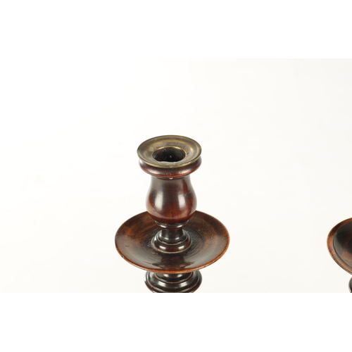 899 - A PAIR OF GEORGE III TURNED MAHOGANY CANDLESTICKS with brass sconces above dished drip tray on balus... 