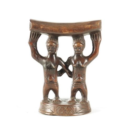 919 - AN AFRICAN HARDWOOD NECK REST with two standing figures. (18cm high 13.5cm wide)