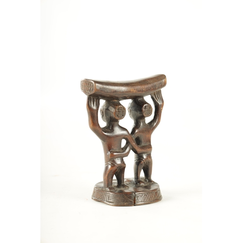 919 - AN AFRICAN HARDWOOD NECK REST with two standing figures. (18cm high 13.5cm wide)