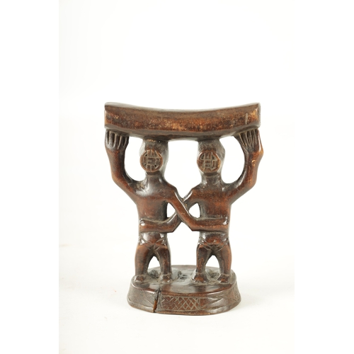 919 - AN AFRICAN HARDWOOD NECK REST with two standing figures. (18cm high 13.5cm wide)