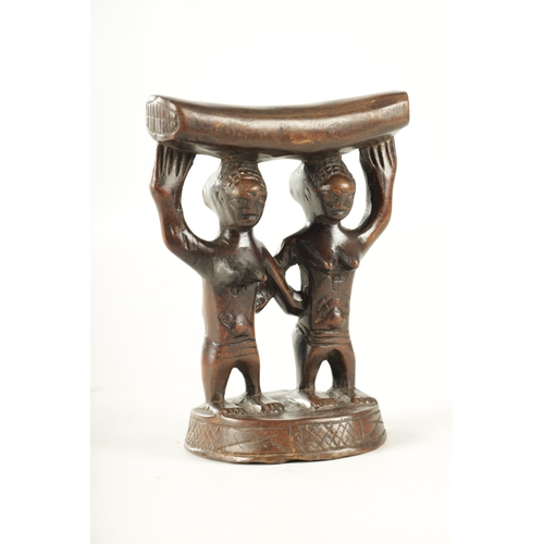 919 - AN AFRICAN HARDWOOD NECK REST with two standing figures. (18cm high 13.5cm wide)