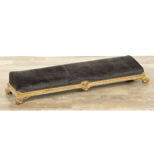 1261 - A 19TH CENTURY CARVED GILT WOOD LONG FOOT STOOL with upholstered top on leaf-carved scrolled feet (1... 