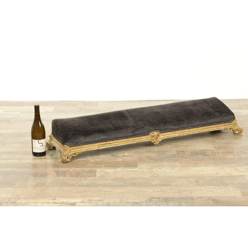 1261 - A 19TH CENTURY CARVED GILT WOOD LONG FOOT STOOL with upholstered top on leaf-carved scrolled feet (1... 