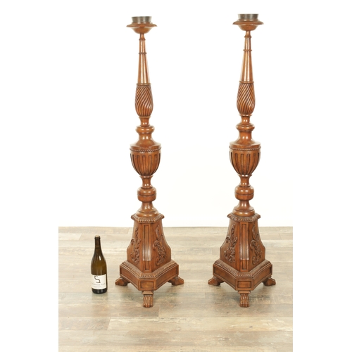 1304 - A PAIR OF 20TH CENTURY WALNUT TORCHERES with bulbous turned stem and raised on triform bases with cl... 