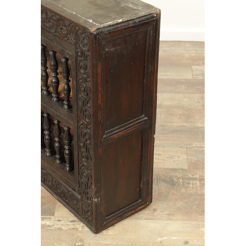 1314 - A 17TH-CENTURY OAK HANGING MURAL / DOLE CUPBOARD with turned spindle hinged doors surrounded by carv... 