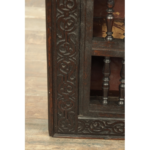 1314 - A 17TH-CENTURY OAK HANGING MURAL / DOLE CUPBOARD with turned spindle hinged doors surrounded by carv... 