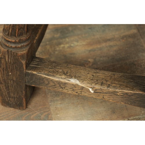 1323 - A 17TH CENTURY STYLE JOINED OAK BOX STOOL with a hinged top above a masked carved frieze raised on c... 