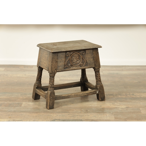 1323 - A 17TH CENTURY STYLE JOINED OAK BOX STOOL with a hinged top above a masked carved frieze raised on c... 