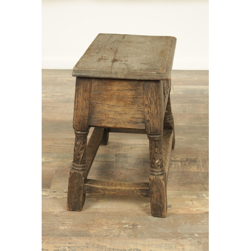 1323 - A 17TH CENTURY STYLE JOINED OAK BOX STOOL with a hinged top above a masked carved frieze raised on c... 