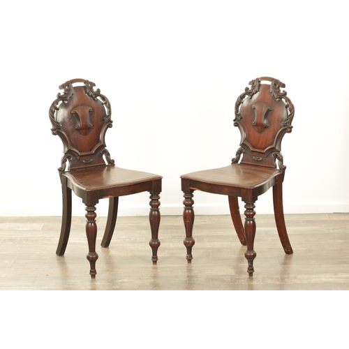 1368 - A PAIR OF 19TH CENTURY MAHOGANY HALL CHAIRS with leaf-carved shaped backs and raised on ring turned ... 